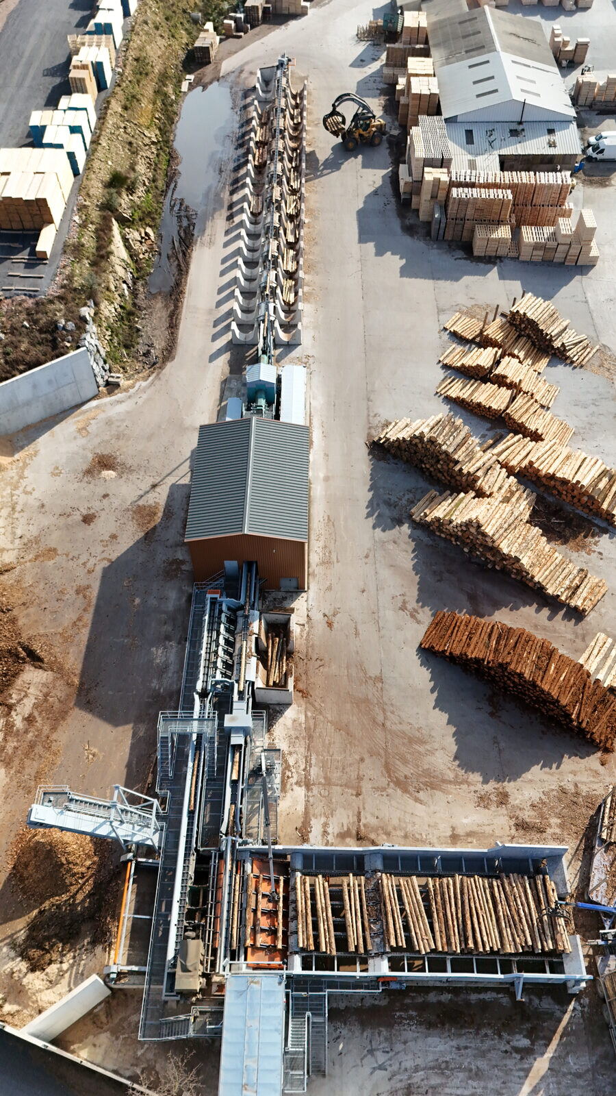 Vue aérienne d'une scierie&nbsp;: bâtiment de sciage et piles de grumes