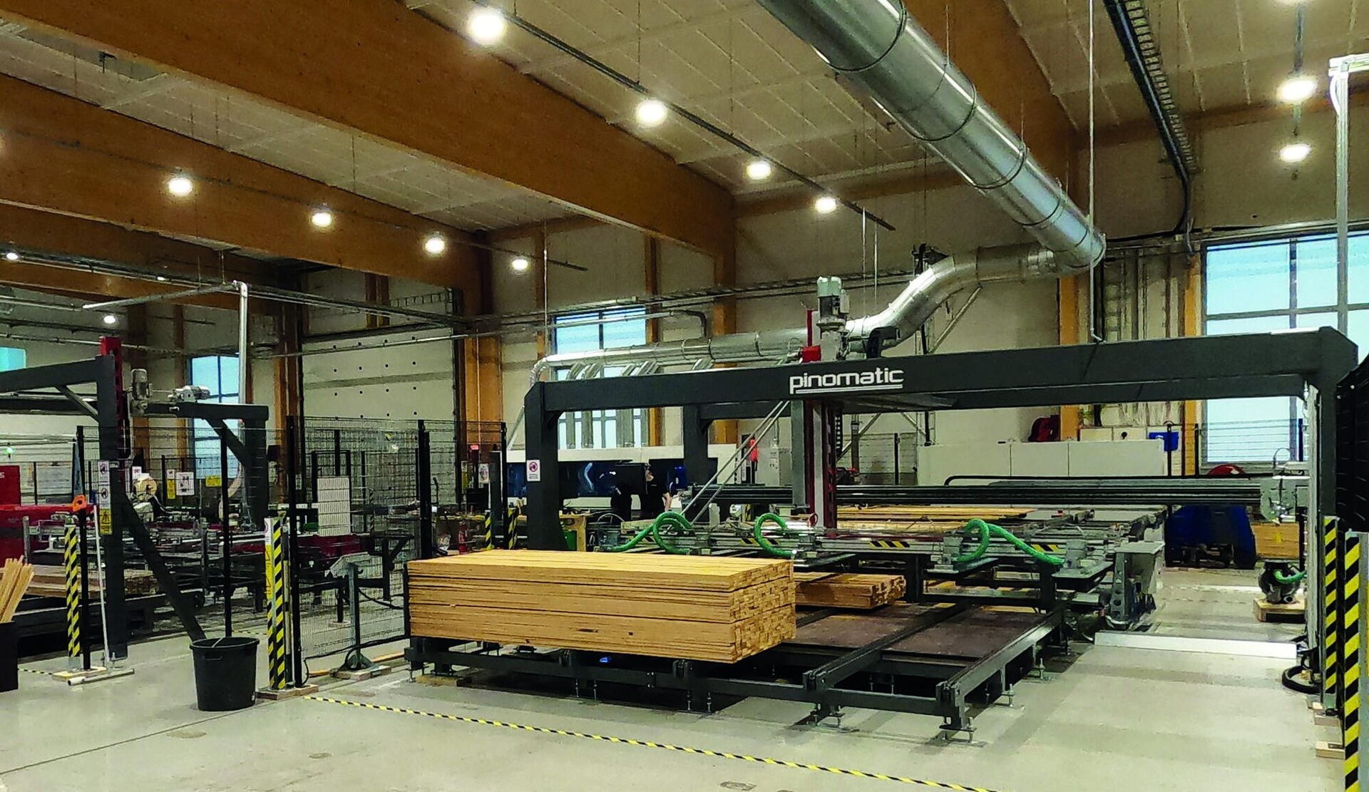 Portique d'empilage au-dessus d'un paquet de lames, dans un hall à charpente en bois